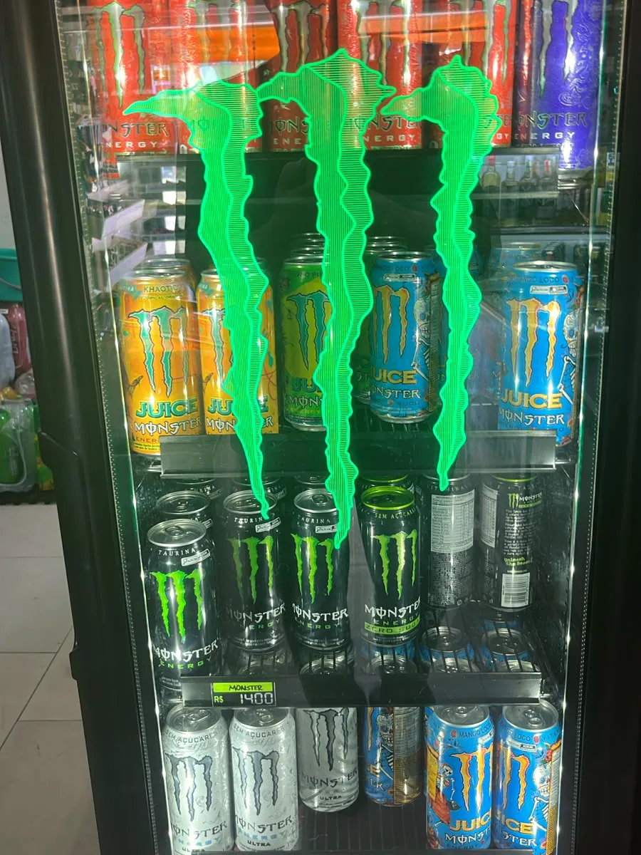 Geladeira da Adega Maui cheia de latas de Monster de vários sabores, com o logo verde aceso na porta