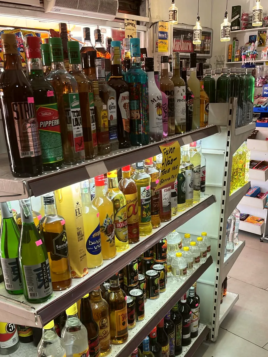 Prateleira de licores e cachaças: Malibu, Baileys, Jose Cuervo, Pitú e 51